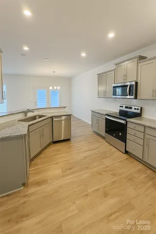 a large kitchen with stainless steel appliances granite countertop a stove top oven a sink dishwasher and white cabinets