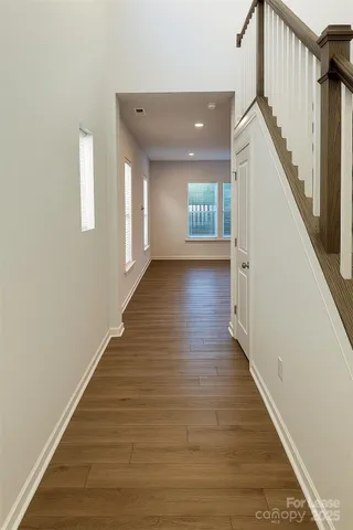a view of a hallway with wooden floor and staircase