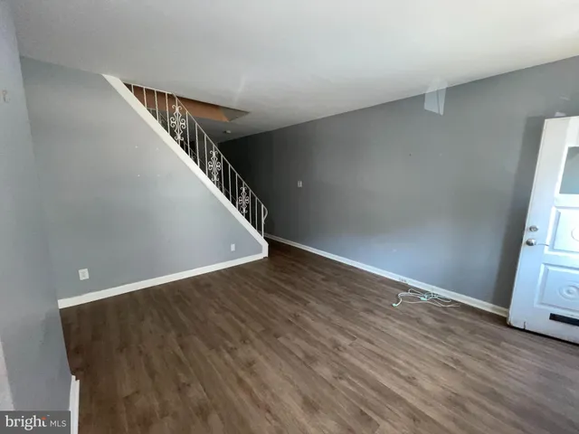 a view of an empty room with wooden floor and stairs