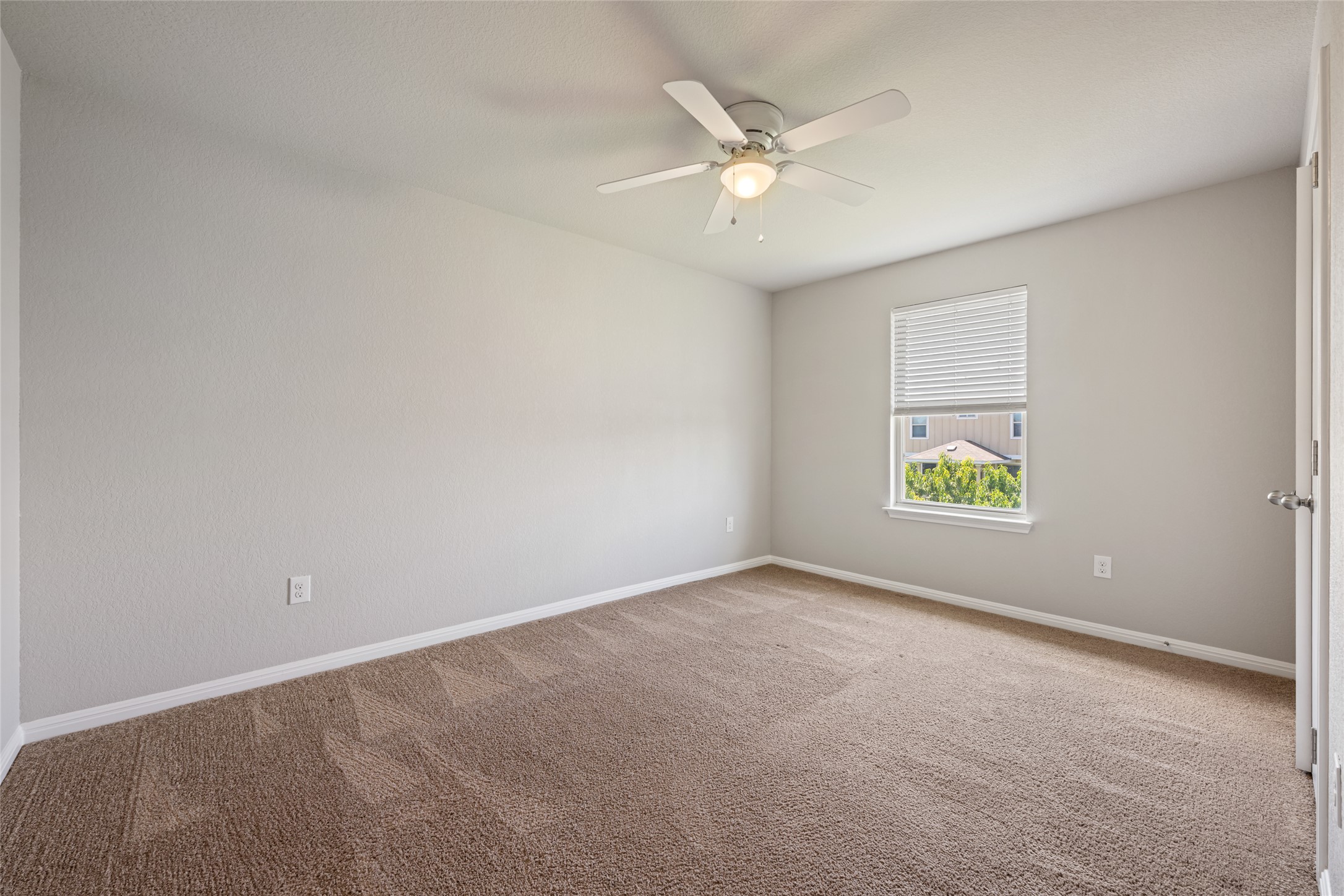 124 Guemal Road Buda, TX 78610 - Photo 33 of 40 A well-lit bedroom features plush carpeting and a ceiling fan for comfort.
