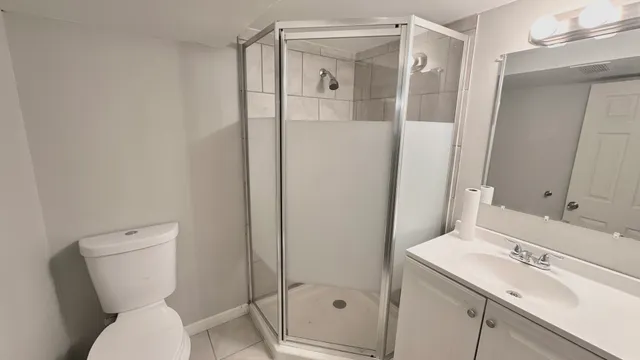 a bathroom with a shower sink vanity mirror and toilet