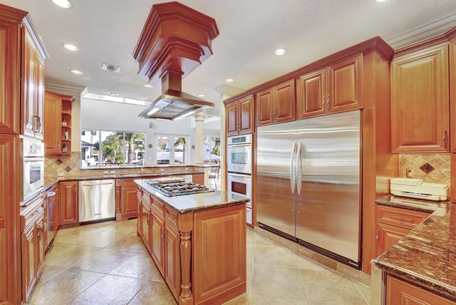 a kitchen with stainless steel appliances kitchen island granite countertop a table chairs in it and wooden floors