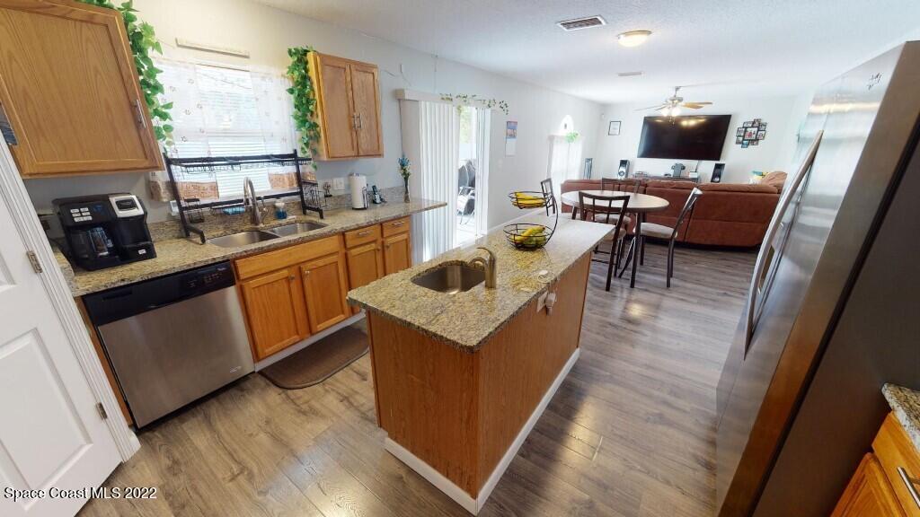 2343 Angel Road Palm Bay, FL 32909 - Photo 4 of 28 a kitchen with stainless steel appliances granite countertop a stove top oven a sink dishwasher and white cabinets with wooden floor