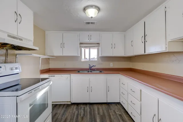 a kitchen with granite countertop white cabinets and white appliances
