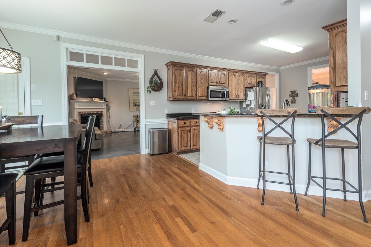 982 Handforth Cove Collierville, TN 38017 - Photo 9 of 25 a kitchen with stainless steel appliances granite countertop a stove top oven a sink dishwasher a dining table and chairs with wooden floor