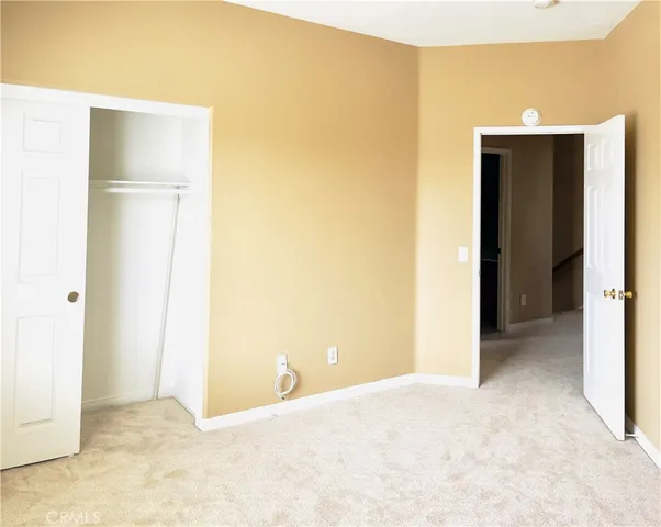 a view of an empty room with closet and a bathroom