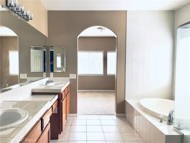 a spacious bathroom with a tub a sink and mirror