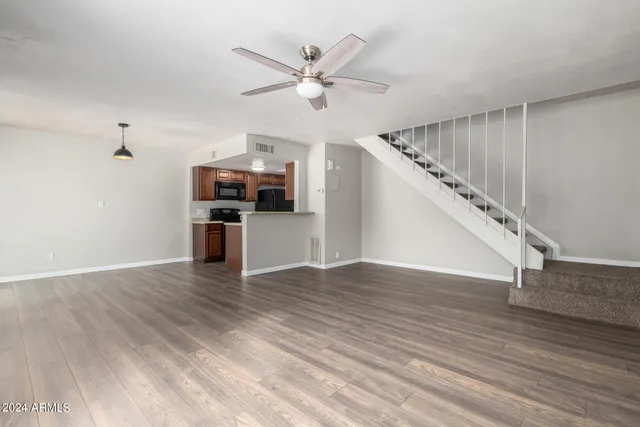 a view of a livingroom with wooden floor and a ceiling fan