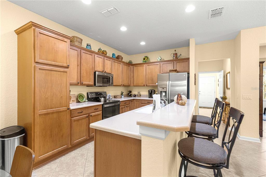 9566 Southwest 70th Loop Ocala, FL 34481 - Photo 7 of 53 a kitchen with a refrigerator a stove top oven a sink dishwasher and white cabinets