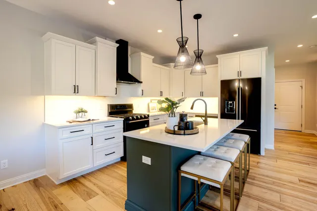a kitchen with stainless steel appliances kitchen island granite countertop a refrigerator a stove a sink dishwasher and a dining table with wooden floor