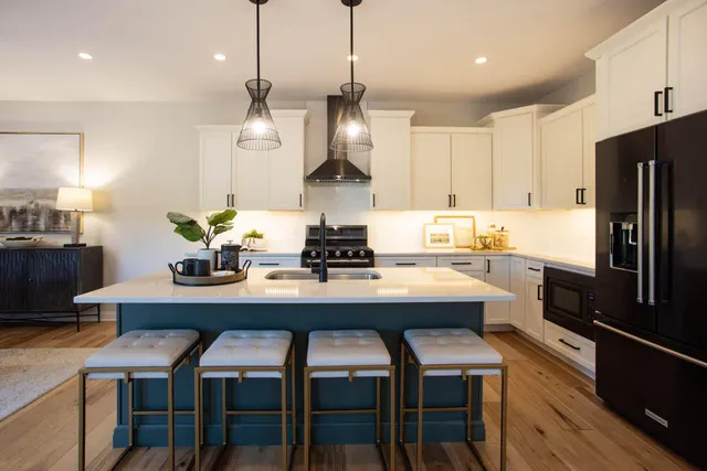 a kitchen with stainless steel appliances granite countertop a dining table chairs refrigerator and microwave