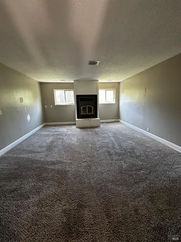 a view of an empty room with a fireplace and a window
