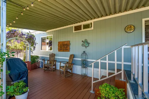 a view of a patio with table and chairs with wooden floor and fence