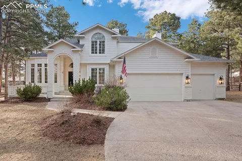 a view of a house with a yard and large tree
