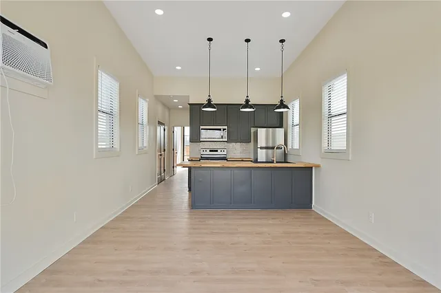 a large kitchen with stainless steel appliances kitchen island a large counter top and a wooden floors