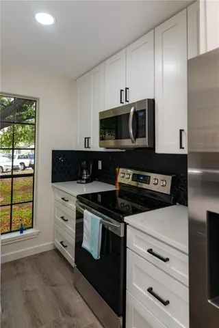 a kitchen with stainless steel appliances white cabinets and a stove top oven