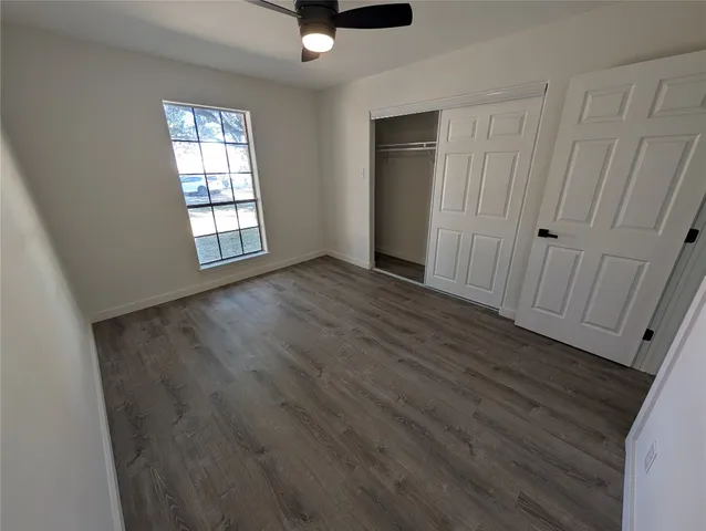 an empty room with wooden floor cabinet and windows