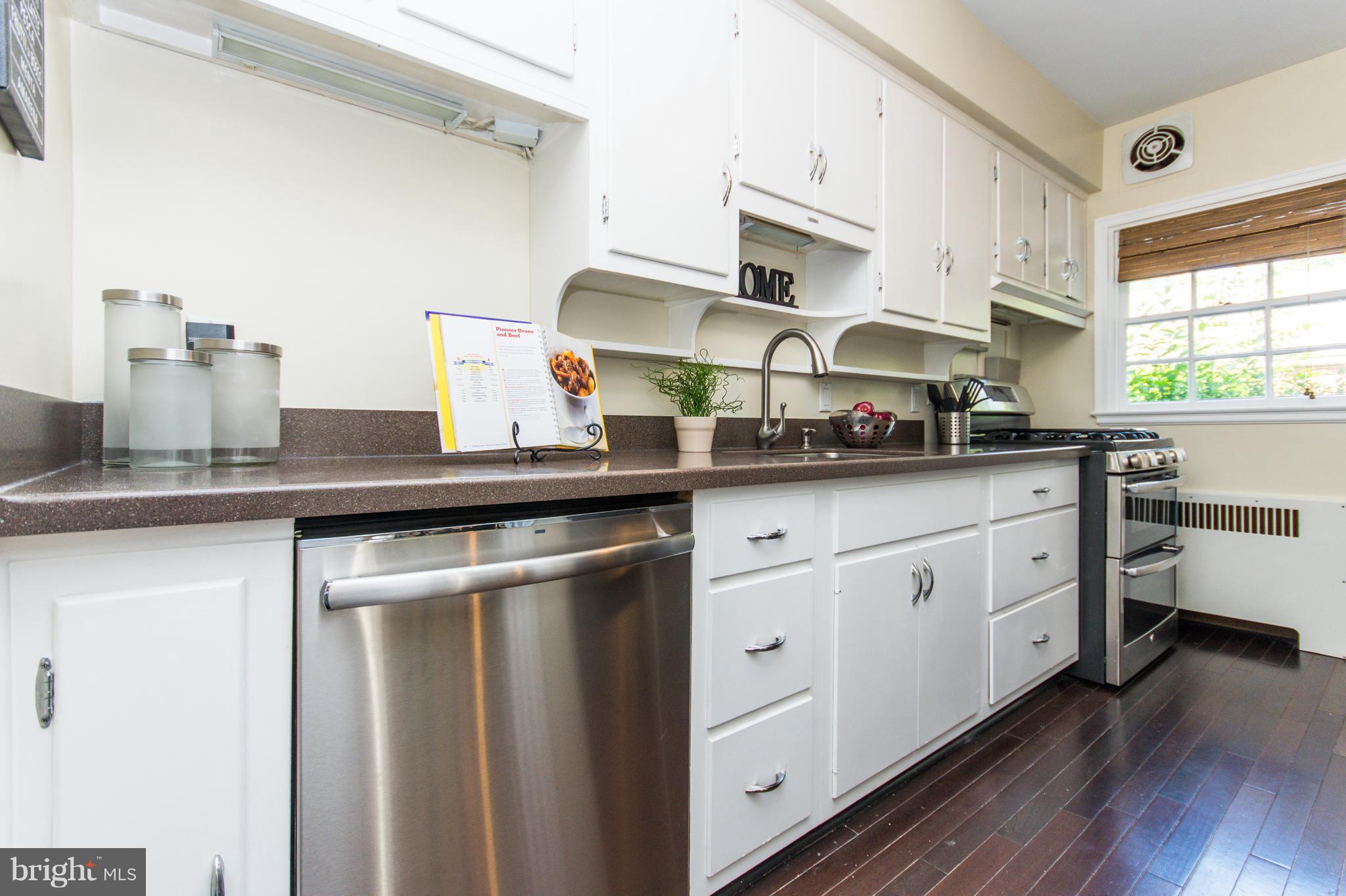 5001 Broadmoor Road Baltimore, MD 21212 - Photo 9 of 26 a kitchen with stainless steel appliances granite countertop a sink a stove and white cabinets with wooden floor
