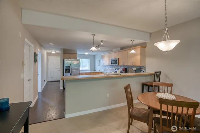 a kitchen with stainless steel appliances granite countertop a dining table chairs and a refrigerator