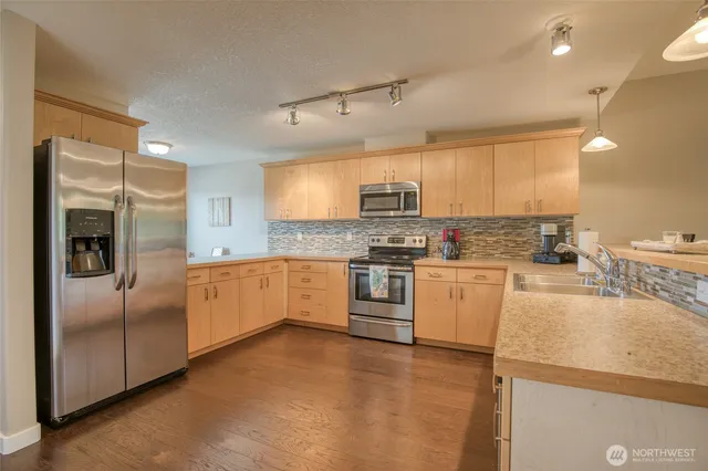 a large kitchen with cabinets a sink and stainless steel appliances