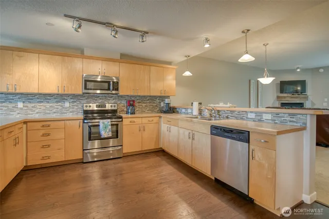 a kitchen with kitchen island granite countertop white cabinets a sink a stove a oven and a refrigerator