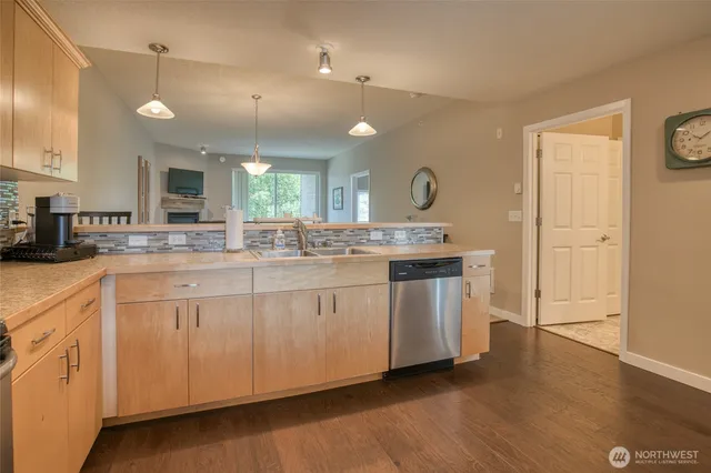 a large white kitchen with a sink a window and stainless steel appliances