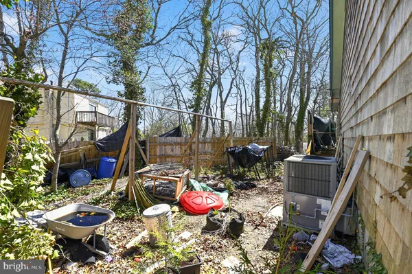 a view of a backyard with table and chairs potted plants and large tree