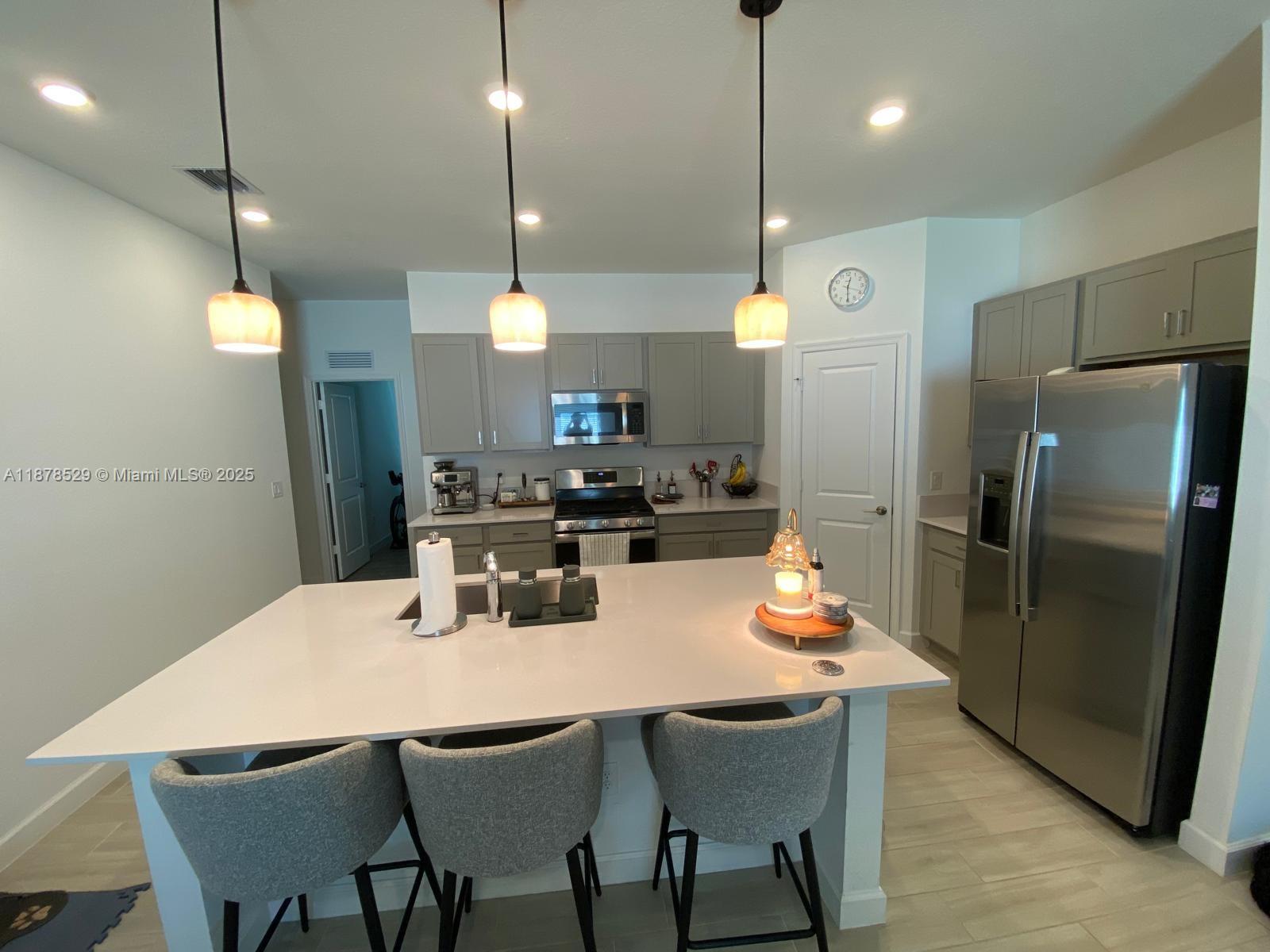 11060 Middle Strm Drive Port St. Lucie, FL 34987 - Photo 16 of 41 a kitchen with stainless steel appliances a dining table chairs and a refrigerator