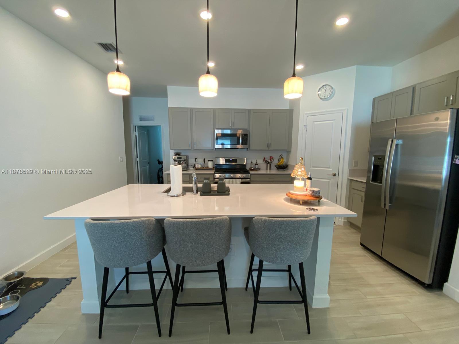 11060 Middle Strm Drive Port St. Lucie, FL 34987 - Photo 20 of 41 a kitchen with stainless steel appliances a dining table chairs and a refrigerator