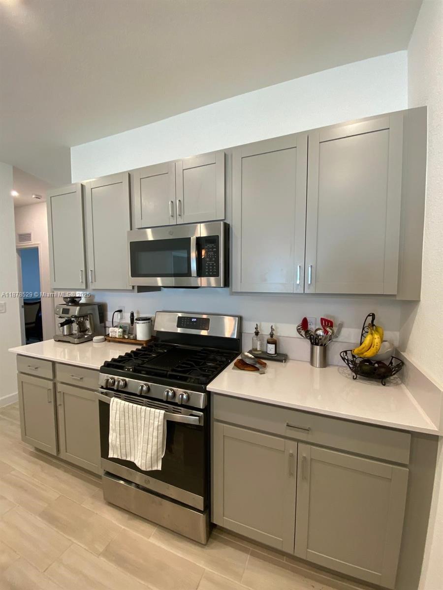 11060 Middle Strm Drive Port St. Lucie, FL 34987 - Photo 27 of 41 a kitchen with stainless steel appliances a stove a sink cabinets and a counter top space