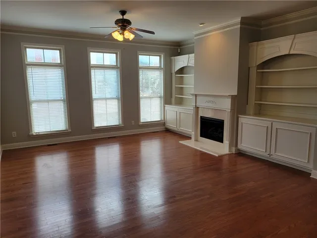 an empty room with wooden floor fireplace and windows