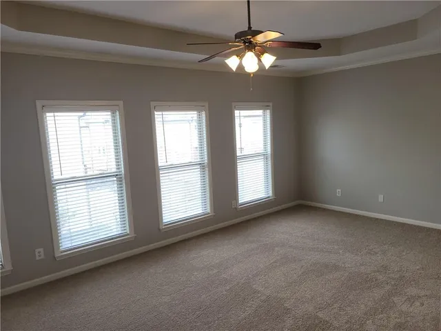 an empty room with chandelier fan and windows