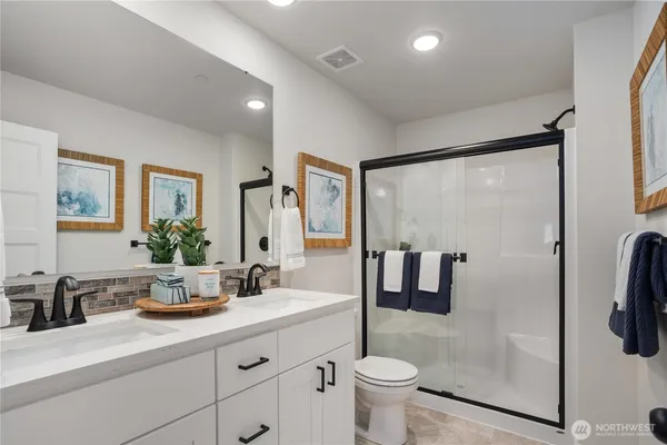 a bathroom with a double vanity sink toilet and shower