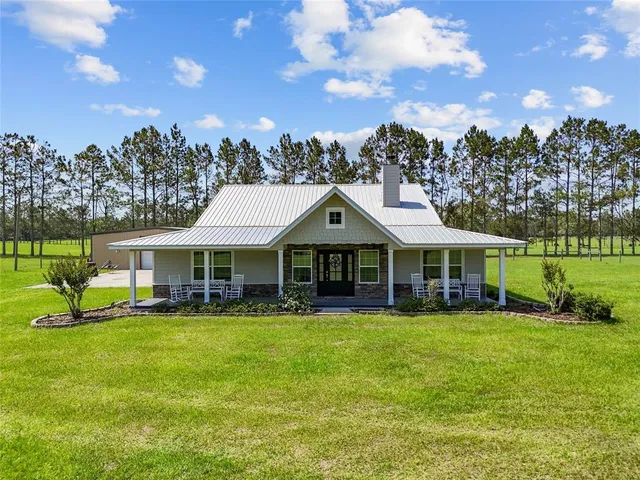 a view of a house with a big yard and large trees