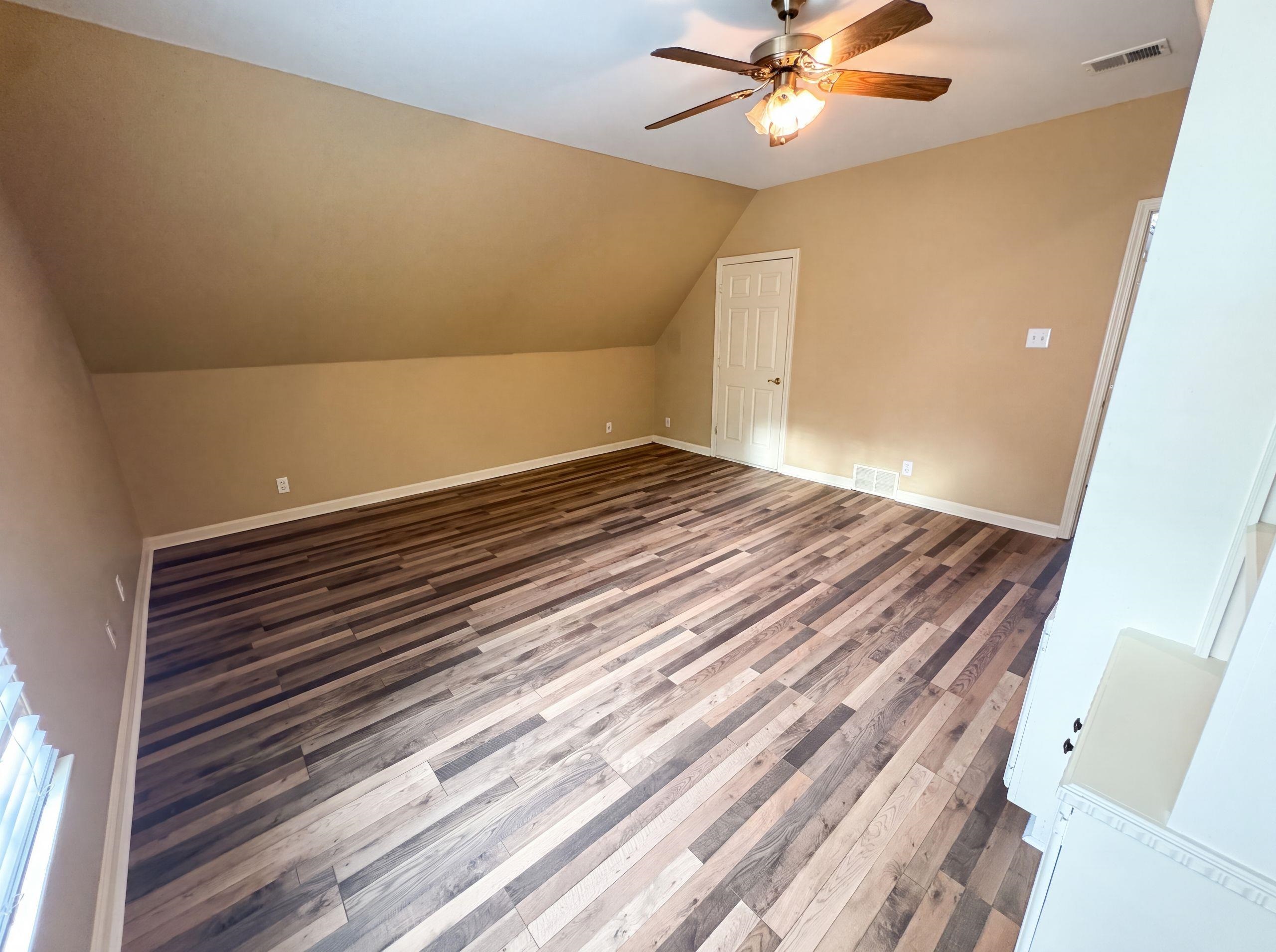9424 Gotten Road Germantown, TN 38139 - Photo 4 of 27 Spacious room featuring multi-tone wood-finish flooring, a ceiling fan with integrated lighting, and a white paneled door