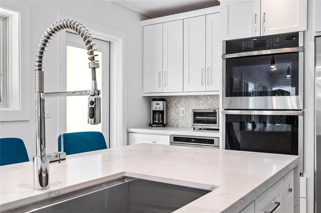 a kitchen with stainless steel appliances a refrigerator a stove and white cabinets with wooden floor