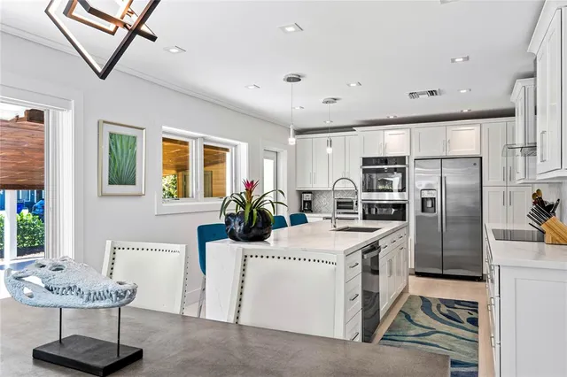 a kitchen with stainless steel appliances kitchen island granite countertop a sink a stove and a refrigerator