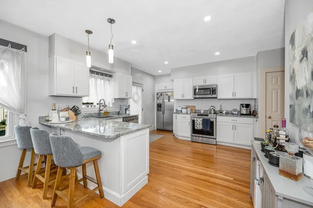 a kitchen with stainless steel appliances kitchen island granite countertop a sink cabinets and wooden floor