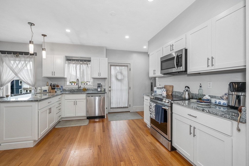 499 Humphrey Street, Unit 3 Swampscott, MA 01907 - Photo 16 of 27 a kitchen with granite countertop white cabinets and stainless steel appliances