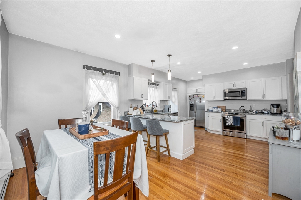 499 Humphrey Street, Unit 3 Swampscott, MA 01907 - Photo 20 of 27 a kitchen with a dining table chairs wooden floor cabinets and stainless steel appliances