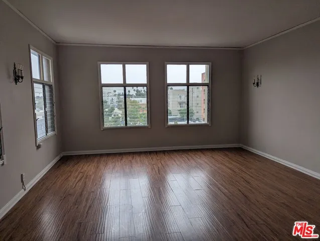 a view of an empty room with wooden floor and windows