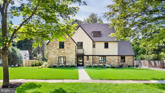 a front view of a house with a garden and trees