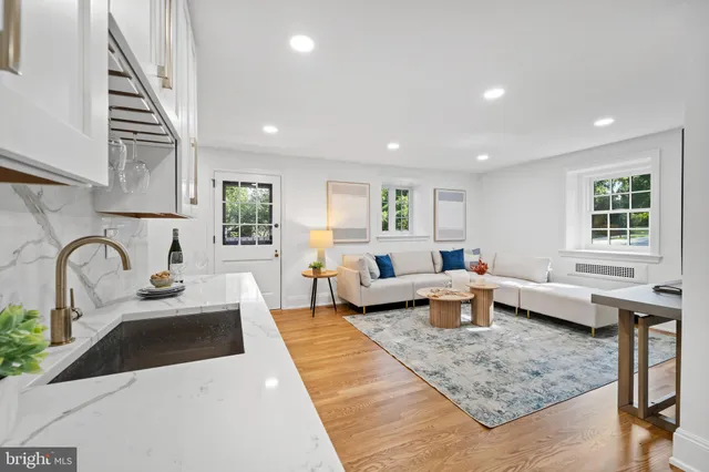 a large white kitchen with stainless steel appliances granite countertop a sink dishwasher a stove and white cabinets with wooden floor