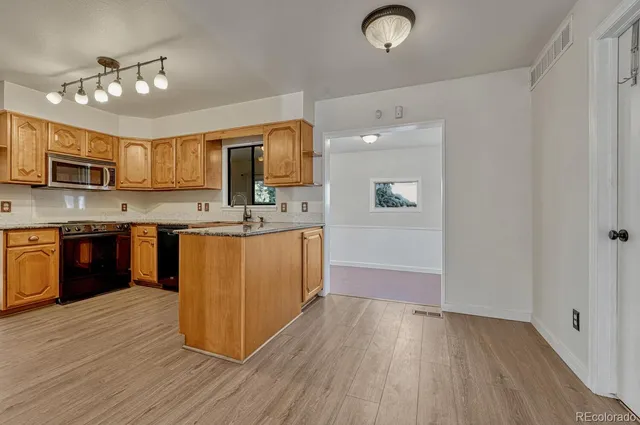 a large kitchen with stainless steel appliances granite countertop a sink dishwasher a stove and a refrigerator