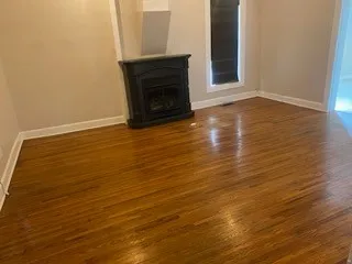 a view of an empty room with wooden floor and a fireplace