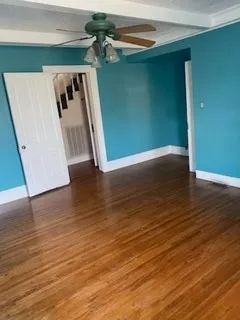 a view of a room with wooden floor and a ceiling fan