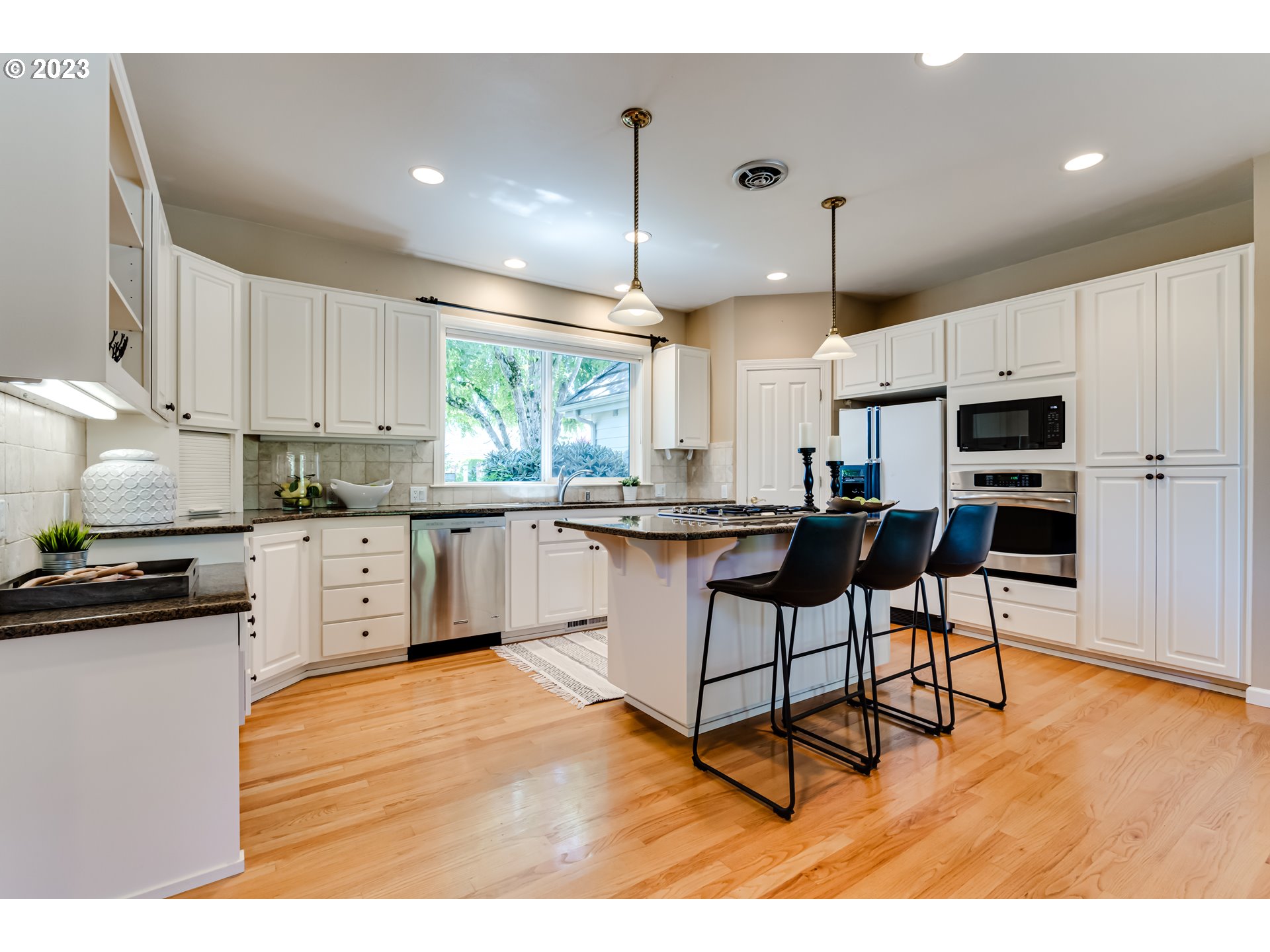 2572 Walnut Ridge Drive Springfield, OR 97477 - Photo 10 of 47 a kitchen with stainless steel appliances kitchen island granite countertop a refrigerator a stove a sink dishwasher and white cabinets with wooden floor