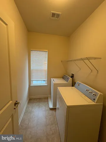 a view of an empty room with chandelier fan and windows