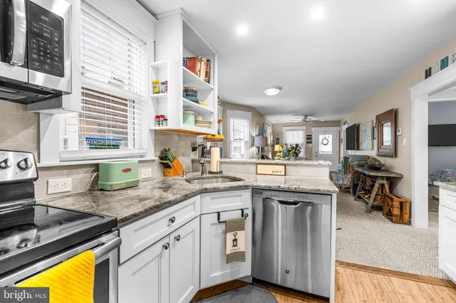 a kitchen with stainless steel appliances granite countertop a sink a stove cabinets counter space and a window