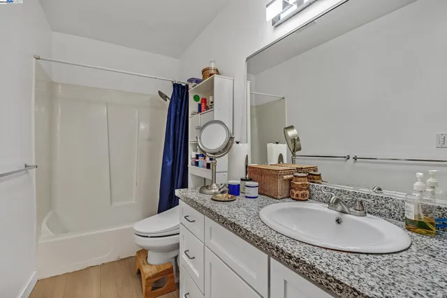 a bathroom with a granite countertop sink a toilet and a mirror